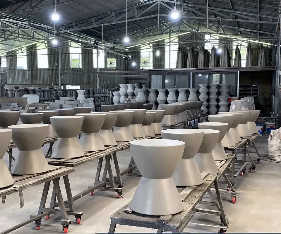 Rows of finished GFRC hourglass stools curing on racks across the Q-Furniture factory floor