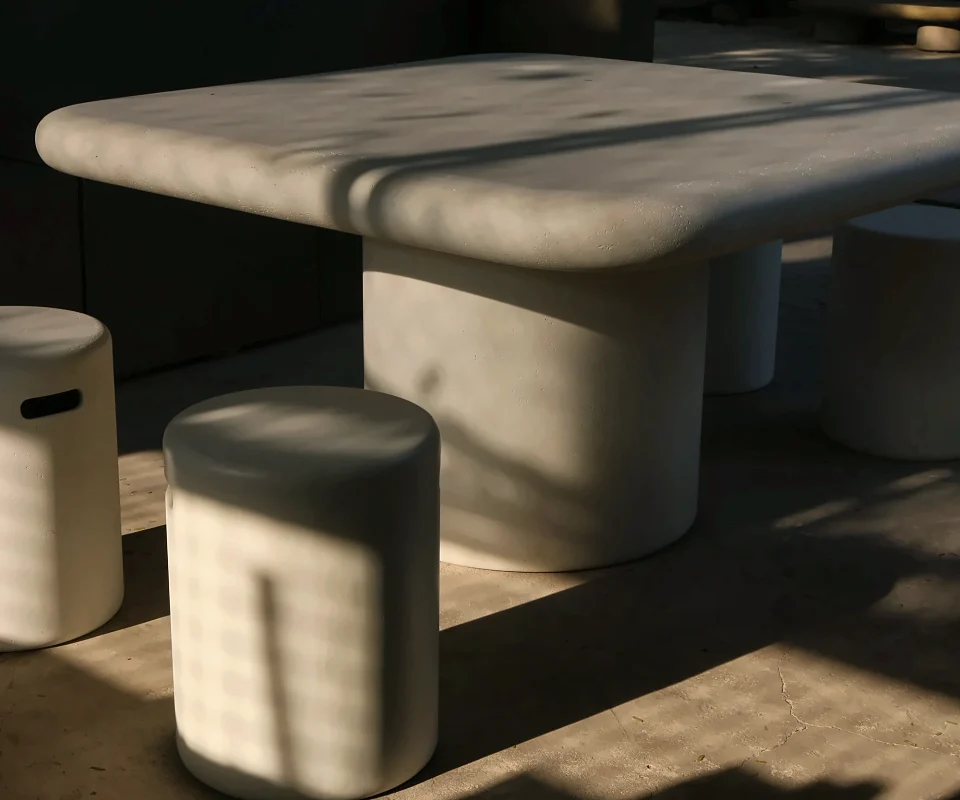 GFRC concrete table and cylinder stools in afternoon light at the Q-Furniture factory